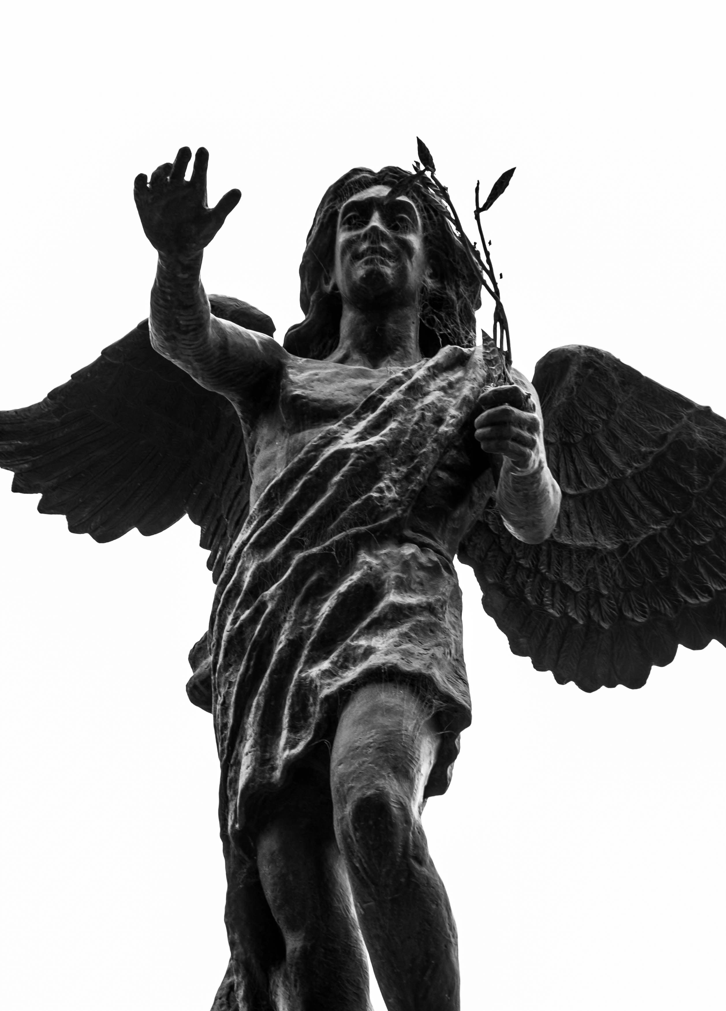 Ángel de bronce en blanco y negro, con un ramo en la mano