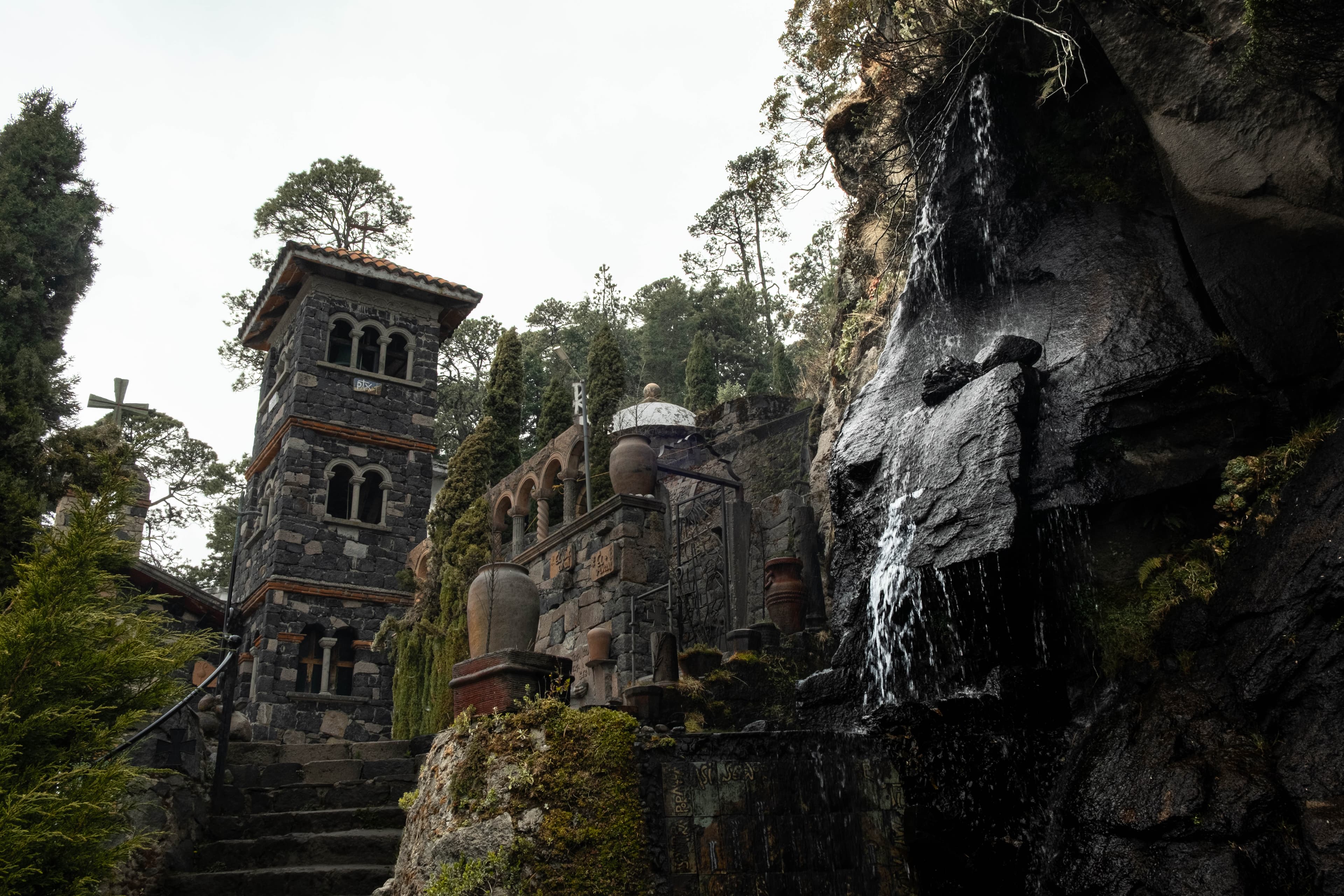Torre de piedra, escalinata y cascada sobre la roca de la casa